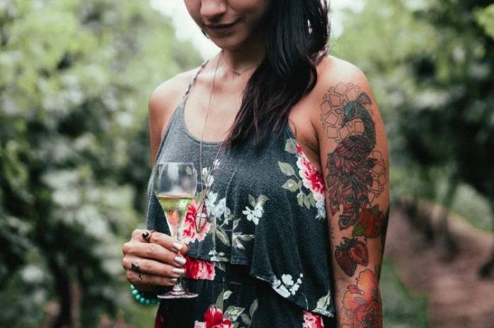 tatoo woman in vineyard with glass of champagne