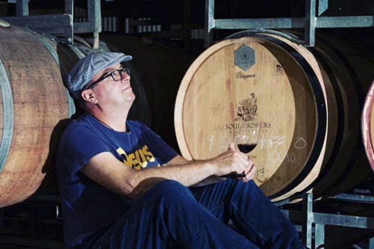 grower drinking wine in front barrels